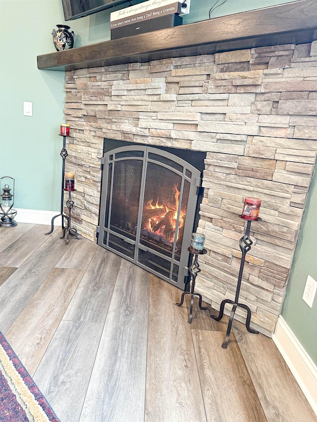 interior details featuring a fireplace, wood finished floors, and baseboards