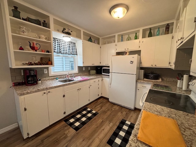 402 Brewster St, Harvey, ND 58341 - kitchen featuring range with electric cooktop, stainless steel microwave, decorative backsplash, freestanding refrigerator, and dark wood-style flooring