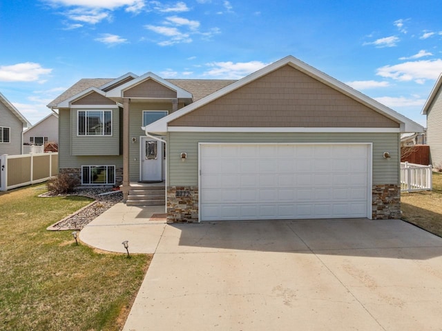 view of front of house with a front yard, fence, driveway, and stone siding