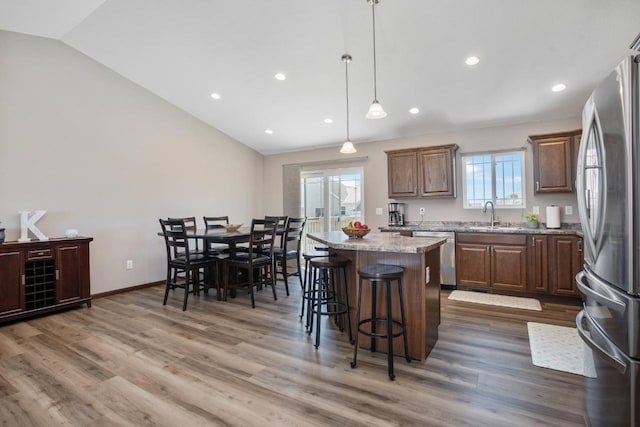 kitchen featuring a breakfast bar area, a center island, a sink, vaulted ceiling, and stainless steel appliances