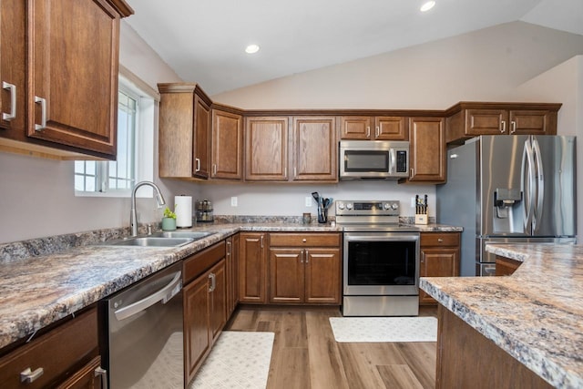 kitchen featuring a sink, light wood-style floors, stainless steel appliances, recessed lighting, and vaulted ceiling