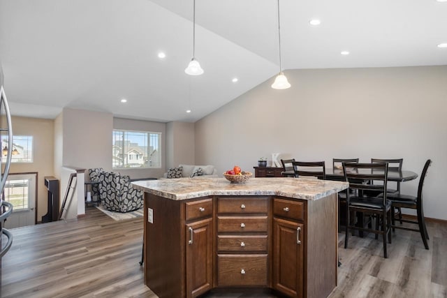 kitchen with a center island, light countertops, wood finished floors, and vaulted ceiling