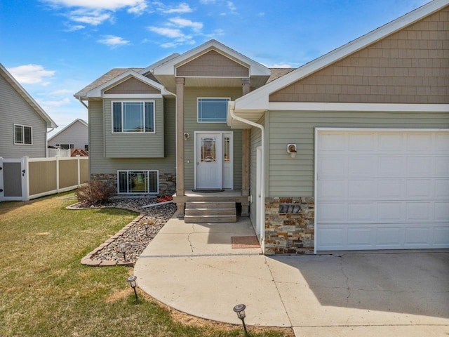 view of front of house featuring an attached garage, fence, a front yard, and stone siding