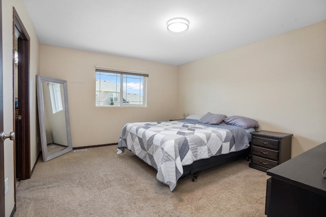 bedroom with baseboards and light carpet