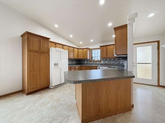 kitchen with decorative backsplash, lofted ceiling, dark countertops, white appliances, and a sink
