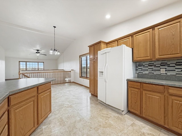kitchen featuring brown cabinetry, white refrigerator with ice dispenser, vaulted ceiling, and a healthy amount of sunlight