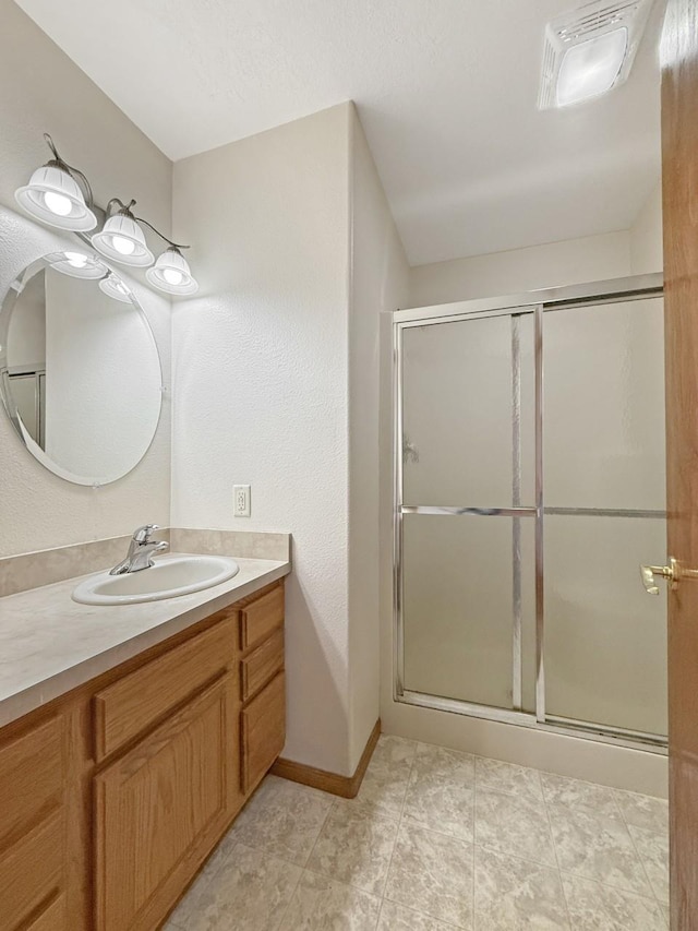 full bath with vanity, baseboards, and a shower stall