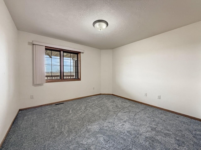 spare room with a textured ceiling, visible vents, baseboards, and carpet