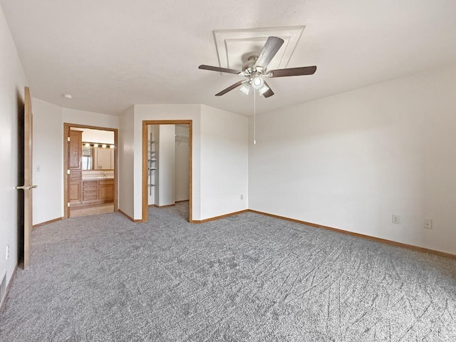 unfurnished bedroom with baseboards, a walk in closet, a closet, and light carpet