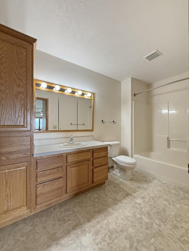 bathroom featuring visible vents, vanity, toilet, a textured ceiling, and shower / washtub combination