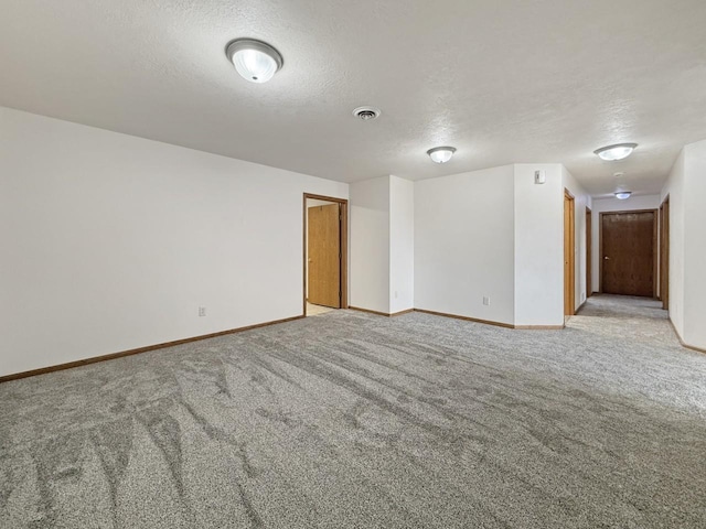 unfurnished room featuring baseboards, visible vents, a textured ceiling, and light colored carpet