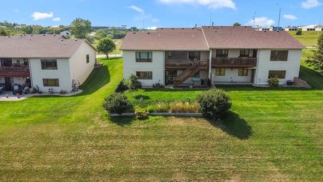 rear view of property with stairway, a yard, and a deck