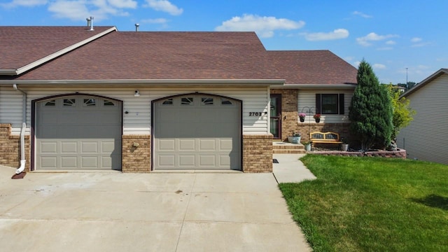 view of front facade with a shingled roof, brick siding, a garage, a front yard, and driveway