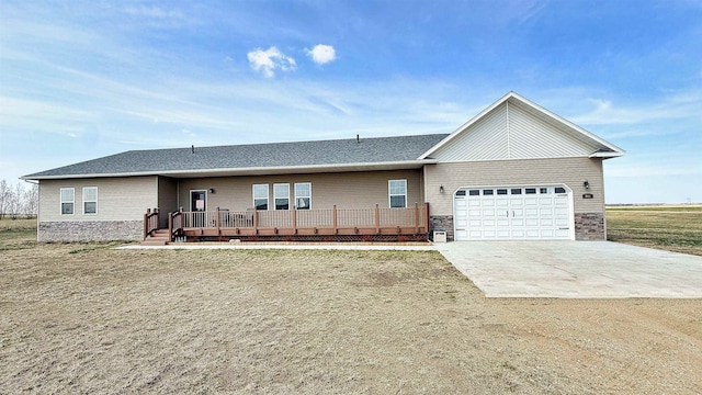 ranch-style home with a deck, driveway, roof with shingles, and a garage