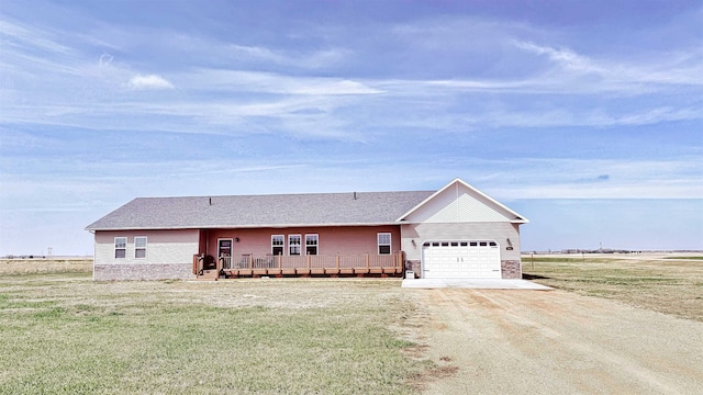 ranch-style home featuring dirt driveway, a wooden deck, a front yard, and a garage