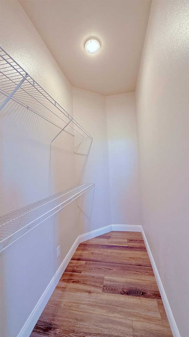 walk in closet with wood finished floors