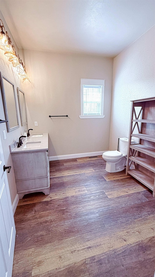 bathroom with vanity, baseboards, toilet, and wood finished floors