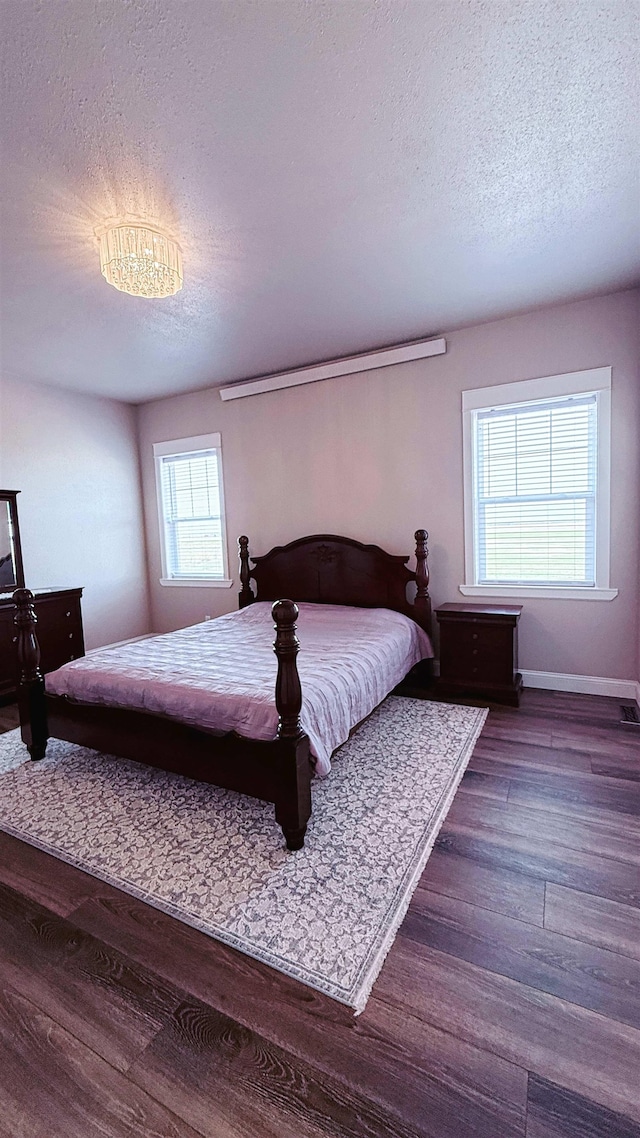 bedroom featuring baseboards, a textured ceiling, and wood finished floors