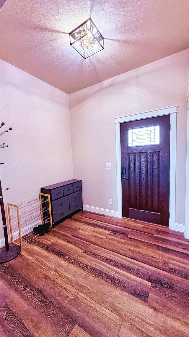 foyer featuring a textured ceiling, baseboards, and wood finished floors