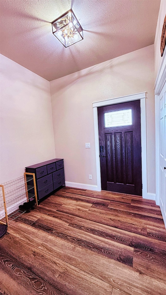 foyer featuring baseboards, a textured ceiling, and wood finished floors