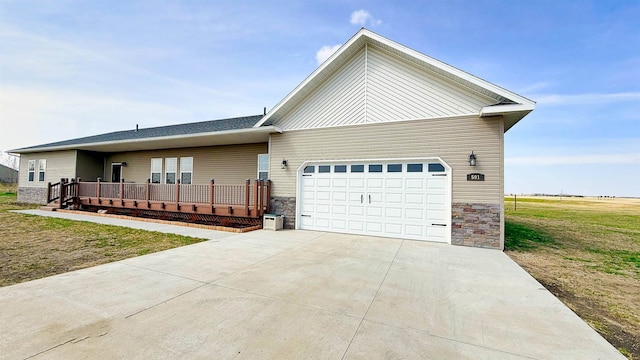 ranch-style house featuring a front lawn, a wooden deck, stone siding, concrete driveway, and an attached garage