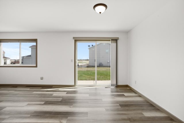 empty room with baseboards, plenty of natural light, and wood finished floors