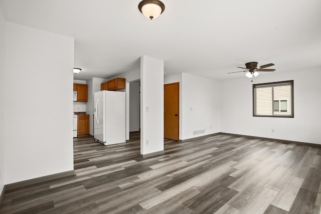 unfurnished living room with baseboards, a ceiling fan, dark wood-style floors, and visible vents