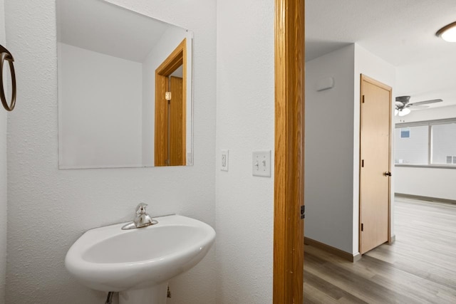 bathroom with a sink, baseboards, ceiling fan, and wood finished floors