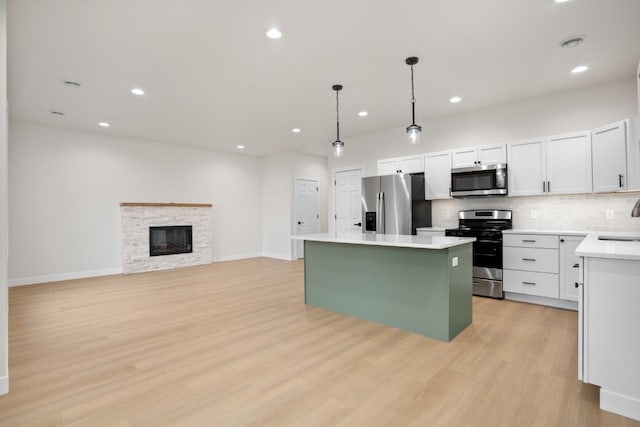 kitchen featuring a sink, a center island, stainless steel appliances, decorative backsplash, and light wood-type flooring