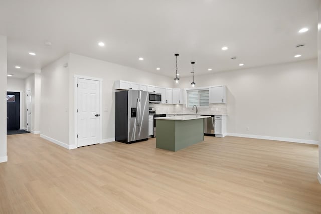 kitchen featuring open floor plan, a center island, white cabinetry, light wood finished floors, and appliances with stainless steel finishes