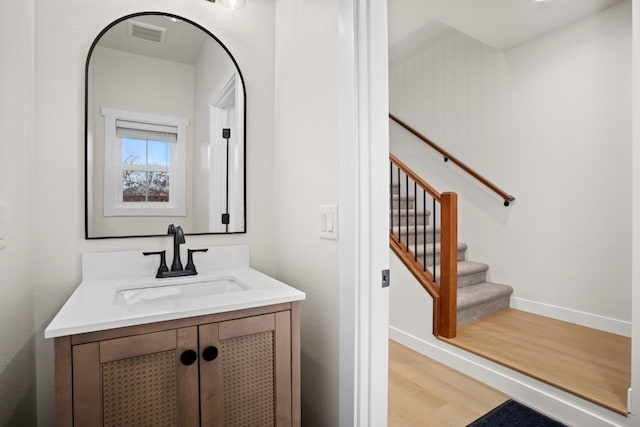 bathroom featuring baseboards, wood finished floors, visible vents, and vanity