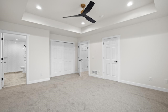 unfurnished bedroom featuring connected bathroom, a raised ceiling, carpet floors, recessed lighting, and baseboards