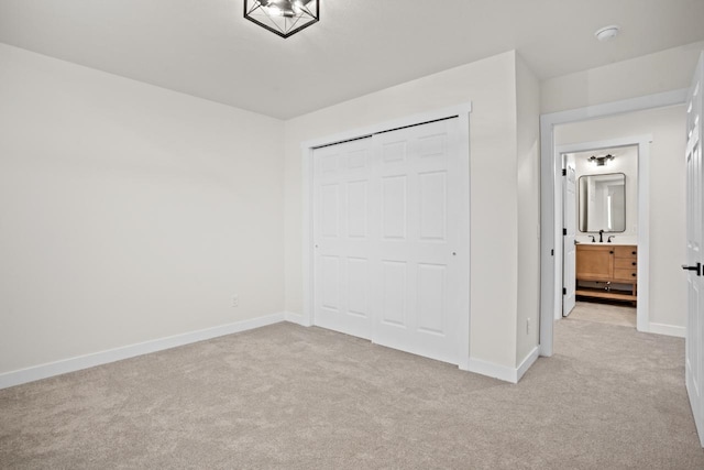 unfurnished bedroom with baseboards, a sink, a closet, and light carpet
