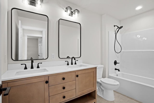 bathroom featuring double vanity, a sink, tub / shower combination, and toilet