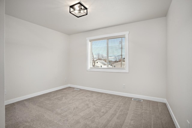 carpeted empty room featuring baseboards and visible vents