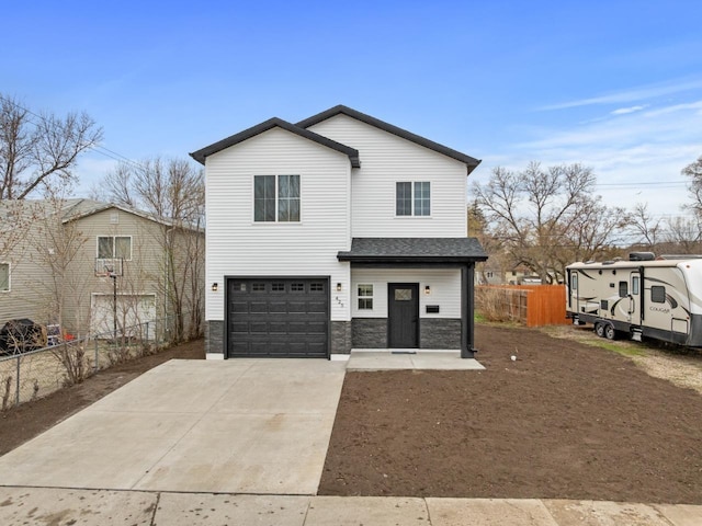 view of front of property with fence, an attached garage, driveway, and stone siding