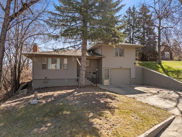 split level home with an attached garage, a front yard, driveway, and a chimney
