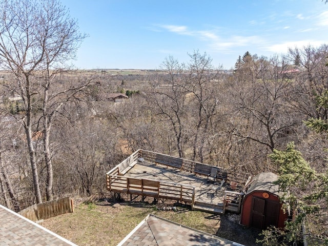 view of yard with fence, a wooden deck, an outdoor structure, and a storage unit
