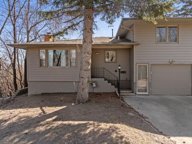 split level home featuring an attached garage, a chimney, and concrete driveway