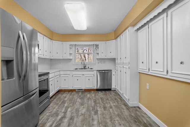 kitchen with white cabinets, appliances with stainless steel finishes, a sink, and light countertops