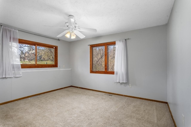 spare room with carpet floors, visible vents, baseboards, a textured ceiling, and a ceiling fan