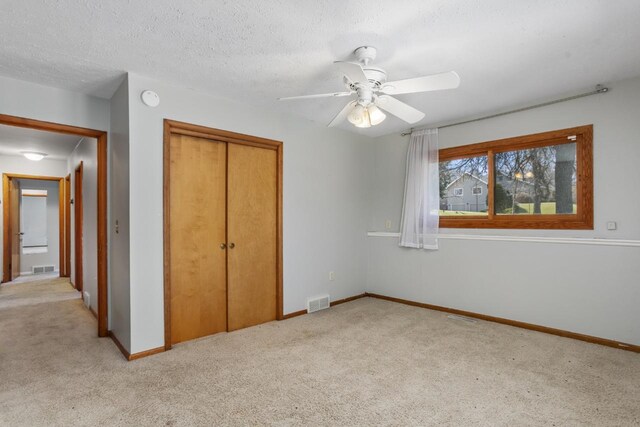 unfurnished bedroom with baseboards, light colored carpet, visible vents, and a closet