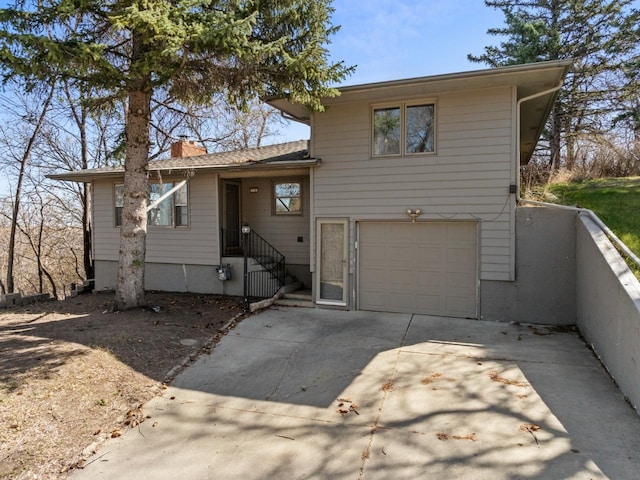 tri-level home with driveway, a chimney, and a garage