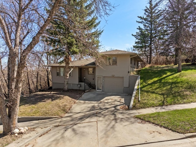 tri-level home featuring a garage, concrete driveway, and a front lawn