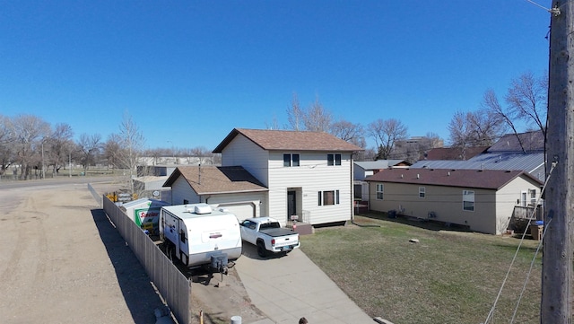 exterior space with a front lawn, fence, an attached garage, driveway, and a residential view