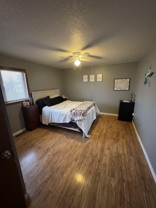 bedroom featuring a textured ceiling, baseboards, a ceiling fan, and wood finished floors