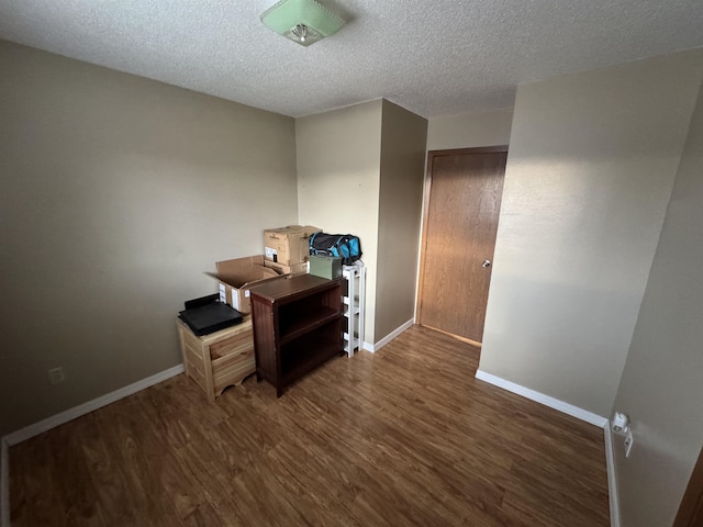 unfurnished office with baseboards, a textured ceiling, and wood finished floors