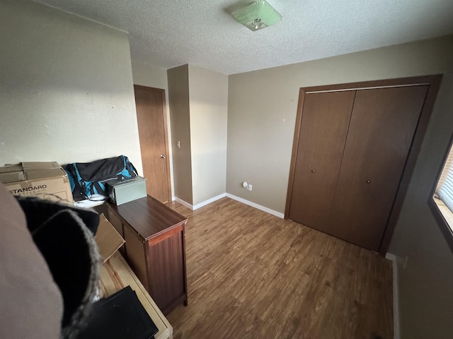 home office with a textured ceiling, baseboards, and wood finished floors
