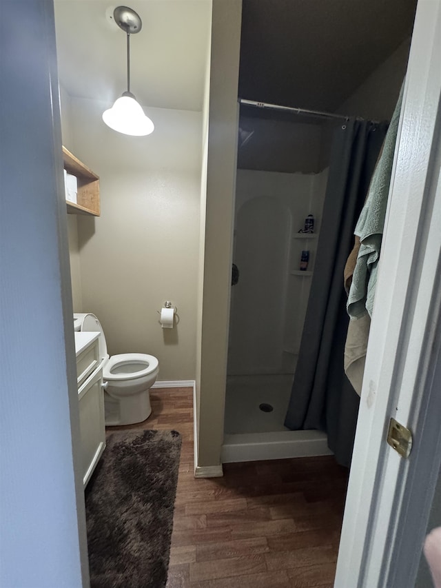 bathroom featuring vanity, a stall shower, toilet, and wood finished floors