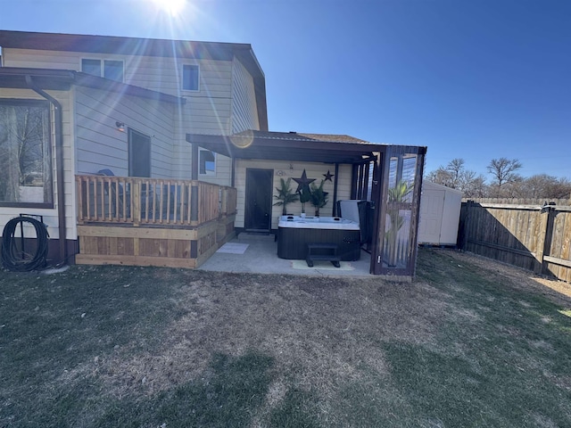 back of house featuring a patio, a fenced backyard, an outbuilding, a hot tub, and a storage shed